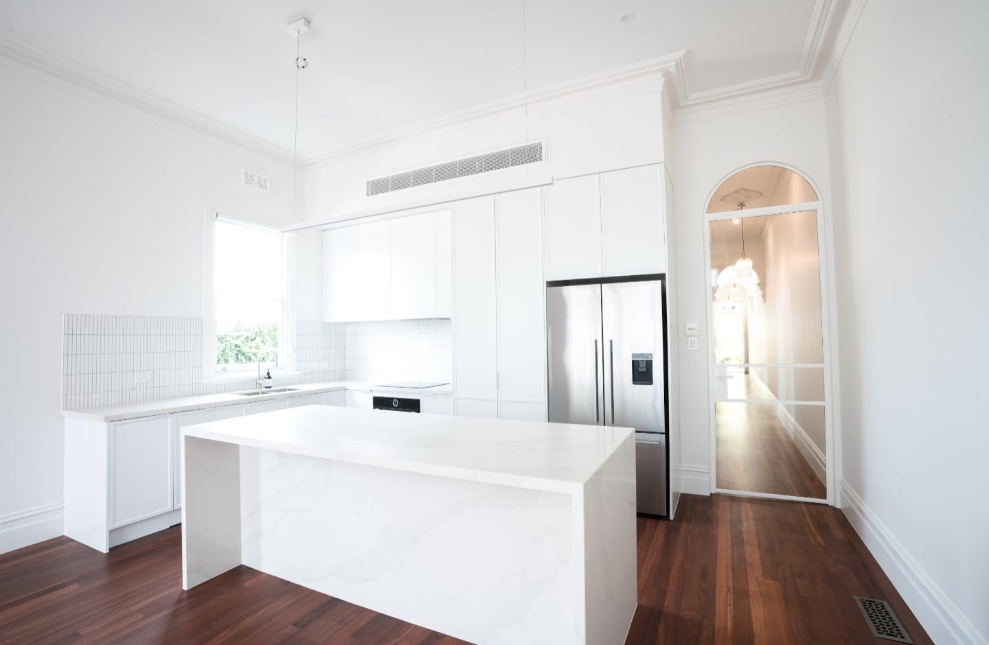 Elegant and modern kitchen renovation by JSG Construct featuring a marble island, white cabinetry, and rich wooden flooring.